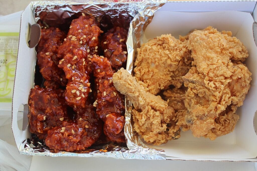 A half-and-half platter of crispy golden fried chicken and glossy, sweet and spicy seasoned chicken (Yangnyeom-chicken).