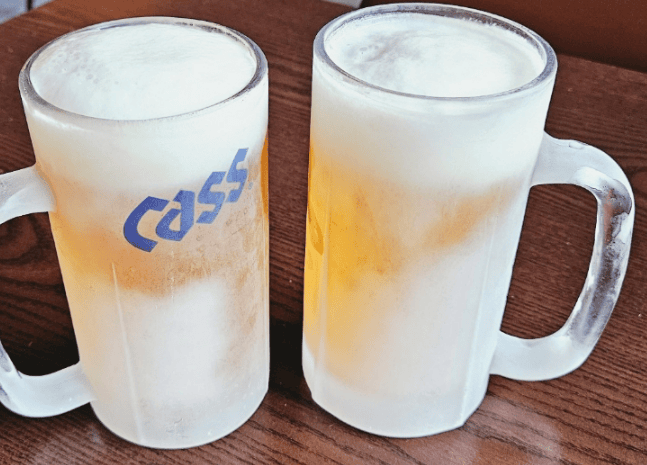 An ice-cold, golden draft beer in a frosted glass with a thin layer of icy slush on top.