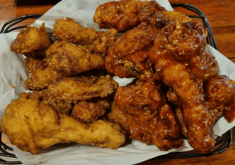 A half-and-half platter of savory soy sauce chicken and garlic-infused Korean fried chicken topped with minced garlic.