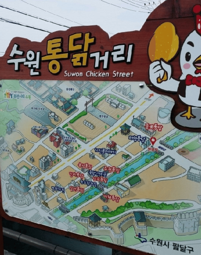 Lively scene of Suwon Chicken Street, featuring traditional whole chickens fried in giant cauldrons and crowds of people waiting in line.