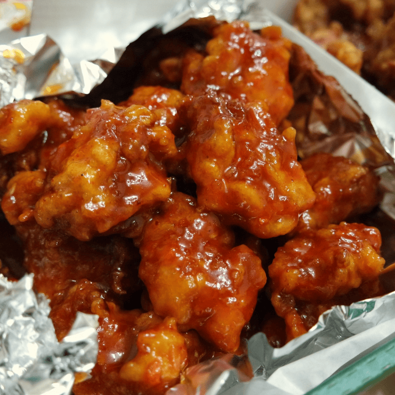 Glossy Korean seasoned chicken (Yangnyeom-chicken) coated in a vibrant, sweet and spicy red sauce.