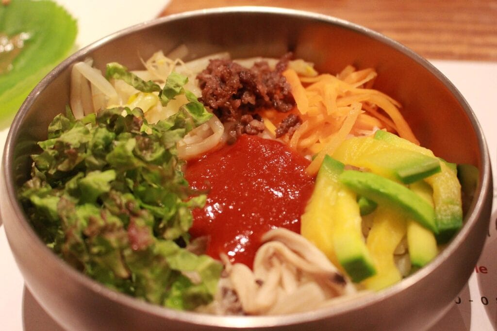 Traditional Korean Bibimbap topped with colorful vegetables, and Gochujang.