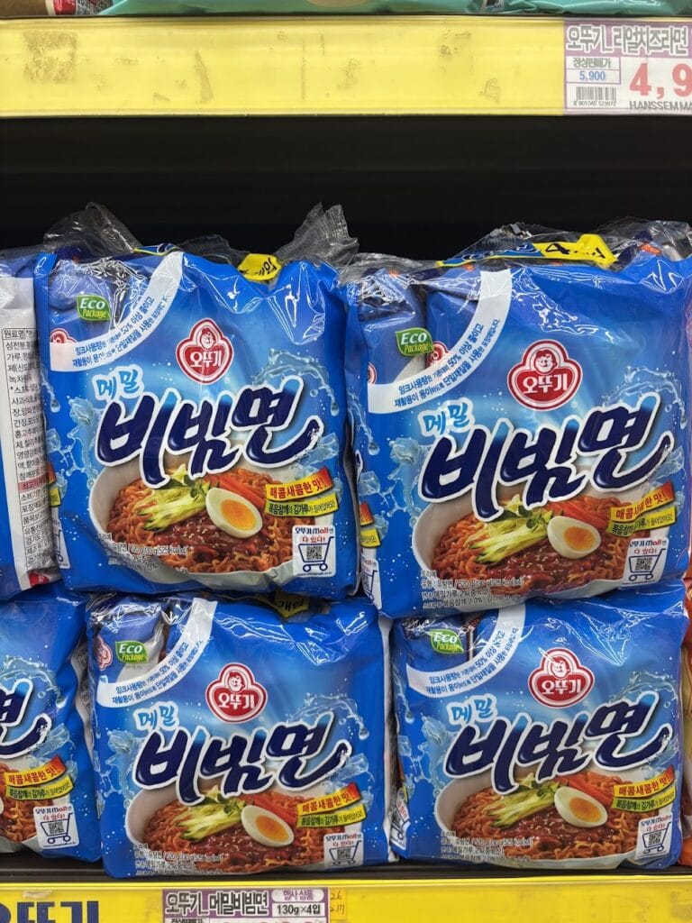 Shelves at a supermarket stocked with Ottogi Buckwheat Bibimmyeon (Cold spicy noodles) in its refreshing sky-blue packaging.