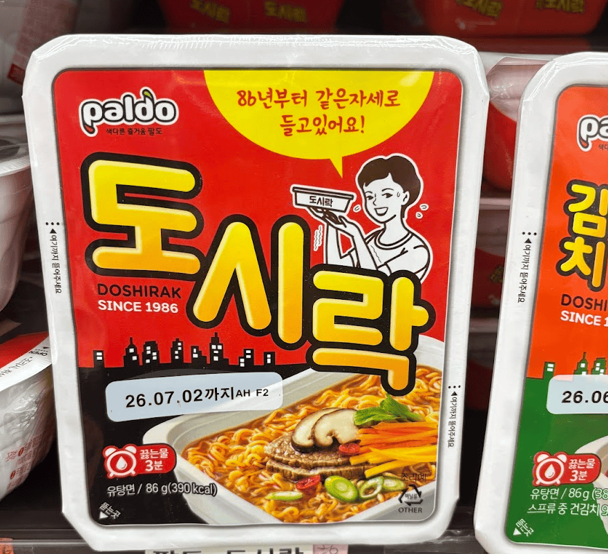 Shelves at a supermarket stocked with Paldo Dosirak (Ramyun) in its iconic rectangular yellow containers.
