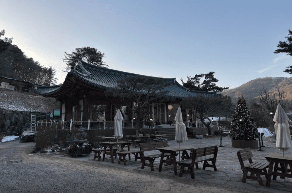 Serene traditional Korean Hanok cafe nestled at the foot of a mountain with outdoor seating.