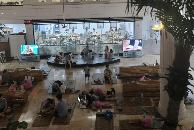 Locals relaxing and napping on the heated floor of a spacious Korean Jjimjilbang (sauna) hall.