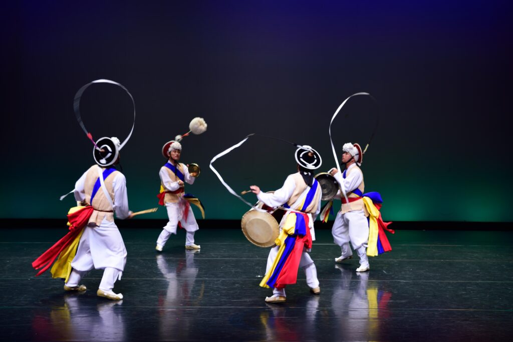 High-energy Samulnori performance with traditional Korean percussion instruments and performers in vibrant folk attire.