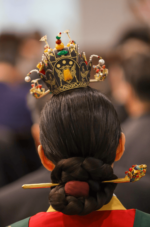 Back view of a traditional Korean hairstyle for women, featuring a classic low bun secured with a decorative Binyeo hairpin. Essential styling detail for wearing a Hanbok at Gyeongbokgung Palace.