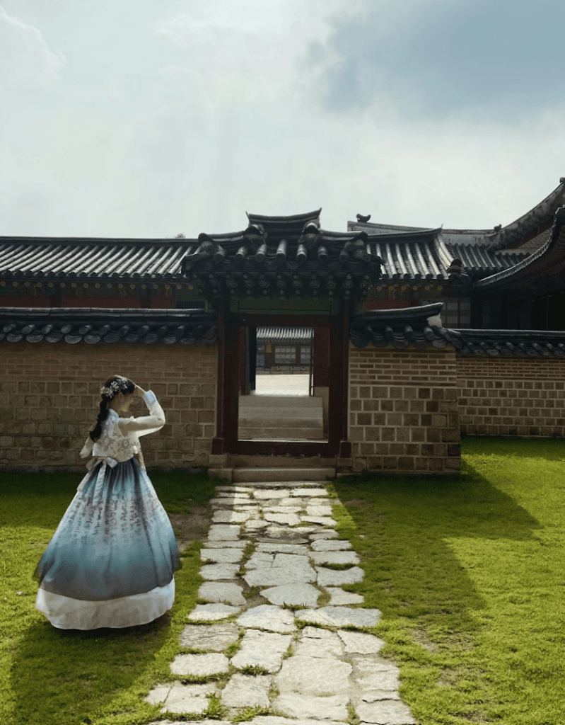 Woman in a stunning traditional Korean dress (Hanbok) strolling through the serene courtyard of Gyeongbokgung Palace. A must-do cultural experience and top photo spot for Seoul travel, Korea.