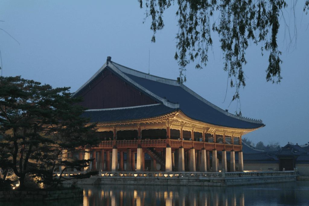Gyeonghoeru Pavilion at night with golden illumination. A stunning architectural landmark of Gyeongbokgung Palace reflected in the water. Top-rated night tour experience in Seoul, Korea.