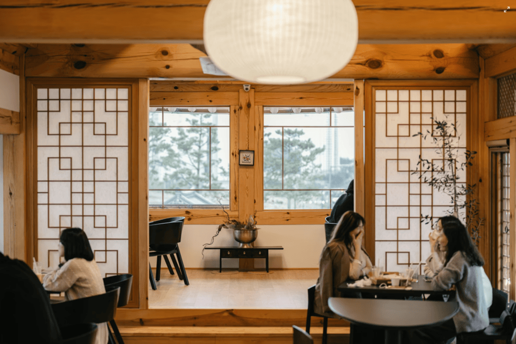 Cozy and authentic interior of a traditional Hanok cafe with people enjoying tea and conversation.