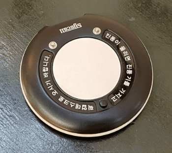 A wireless cafe pager (vibration bell) sitting on a wooden table, waiting for a drink order.