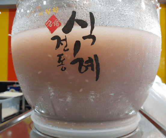Icy and refreshing Sikhye in a slush machine, showcasing its authentic rice grains and cold texture.