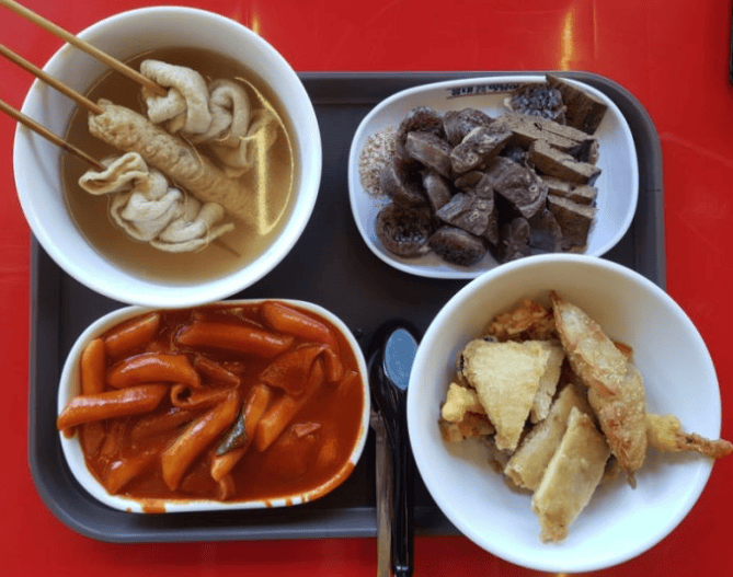 A colorful platter of Tteokbokki, Soondae, and fried snacks, and fish cake, the ultimate #SeoulFoodie experience in a local market.