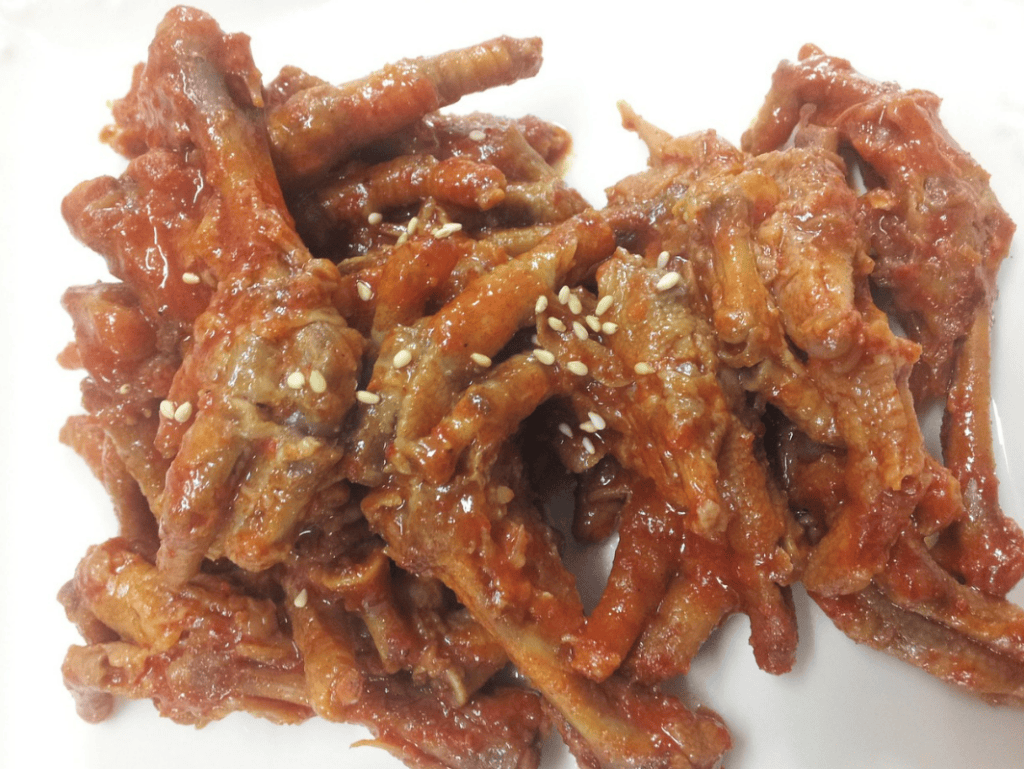 A close-up of charcoal-grilled Korean style spicy marinated chicken feet, known as Dakbal.