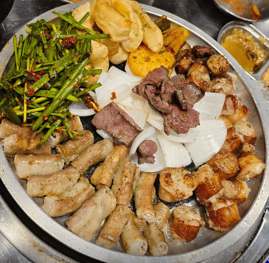 Close-up view of a classic Korean K-BBQ dish: savory, seasoned grilled beef intestines (Gopchang and Daechang).