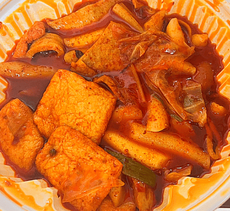 A large bowl of Mara Tteokbokki (Korean rice cakes in spicy Sichuan peppercorn sauce), filled with chewy rice cakes, beef slices, tofu skin, and wide glass noodles.