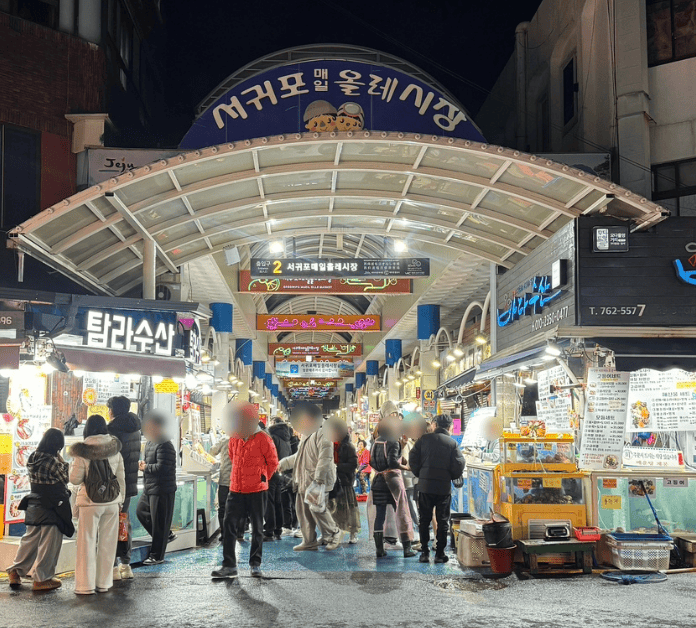 The main entrance of Seogwipo Maeil Olle Market in Jeju Island, featuring its large colorful signage and traditional market architecture.