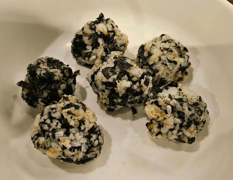 Bite-sized Korean rice balls (Jumeokbap) covered in seasoned seaweed flakes, perfect for pairing with fiery Dakbal (chicken feet).