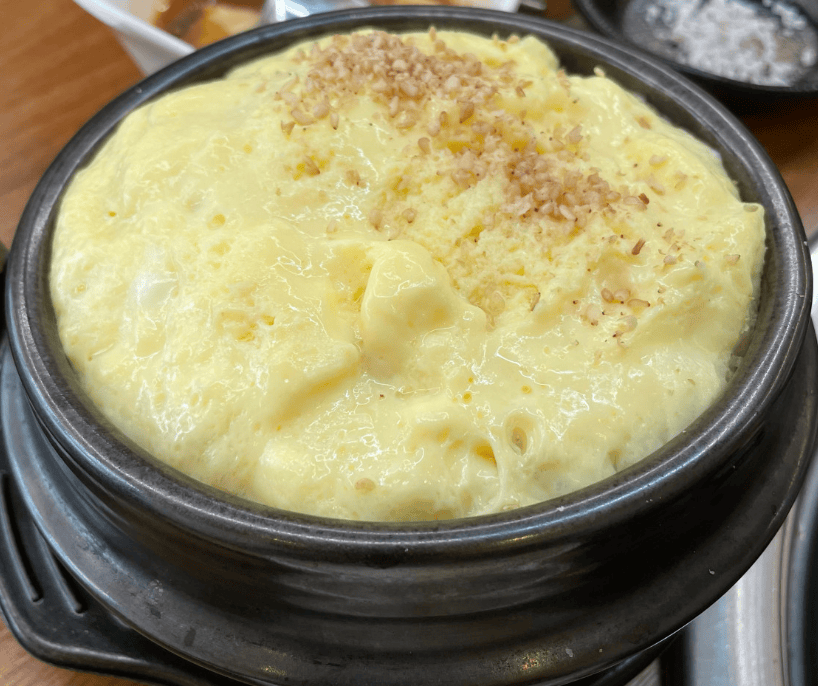 Fluffy and steaming Korean steamed egg (Gyeran-jjim) in a stone pot, served as a soothing side dish for spicy chicken feet.