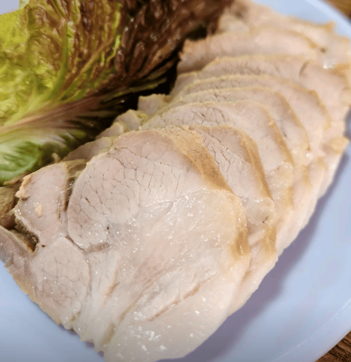 Traditional Korean dish Bossam featuring shiny, moist boiled pork belly slices