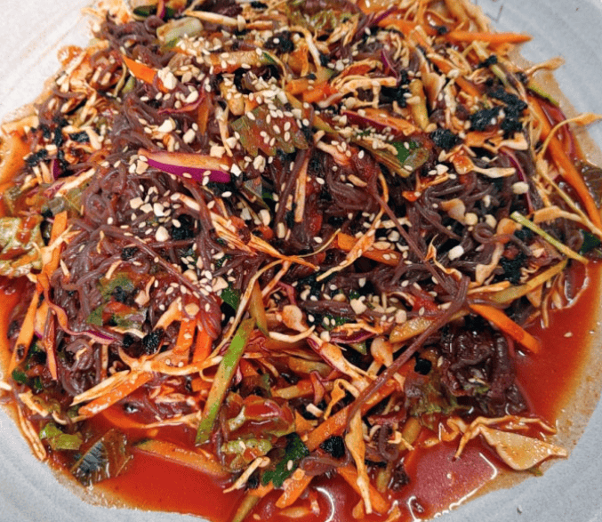 Mouth-watering Korean spicy buckwheat noodles (Makguksu) tossed with crisp lettuce, cabbage, carrots, and a savory, glossy red dressing.