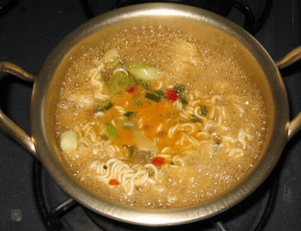 Delicious Korean Ramyun boiling in a classic, dented yellow aluminum pot (Yangeun-naembi).