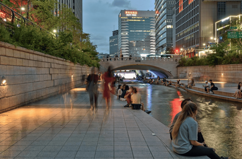 Locals relaxing by the water at Cheonggyecheon Stream after work, enjoying a quiet moment in the city.