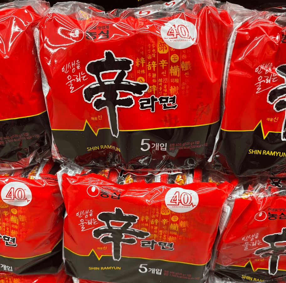 Stack of iconic red Nongshim Shin Ramyun packs on a Korean supermarket shelf.