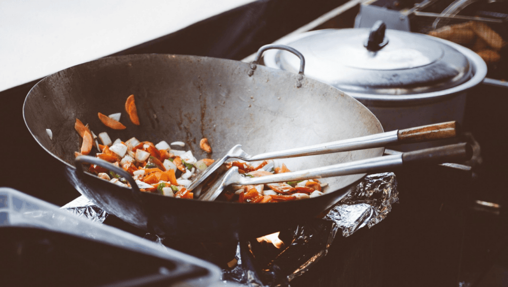 Traditional wok cooking with high-heat stir-frying in a Korean-Chinese restaurant kitchen, creating the signature smoky flavor of Jajangmyeon and Jjamppong.