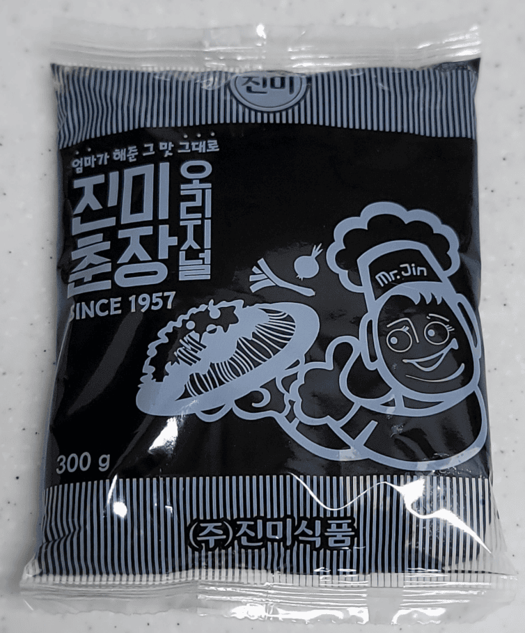 A retail package of Korean Chunjang (black bean paste), showing the thick, fermented black sauce used as the essential base for homemade Jajangmyeon.
