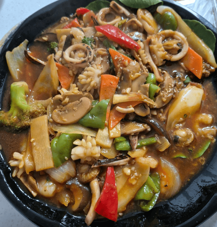 A luxurious platter of Palbochae (Eight Precious Treasures), featuring stir-fried sea cucumber, shrimp, squid, and abalone with colorful vegetables in a savory starch sauce.