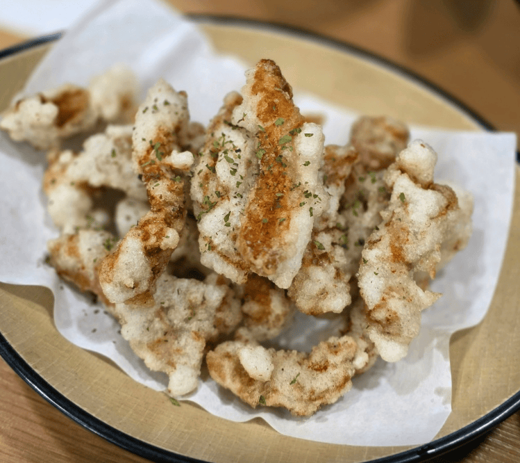 A plate of golden-brown, deep-fried pork pieces (Tangsuyuk) with a visible crispy texture, served fresh and hot in a traditional Korean-Chinese restaurant setting.