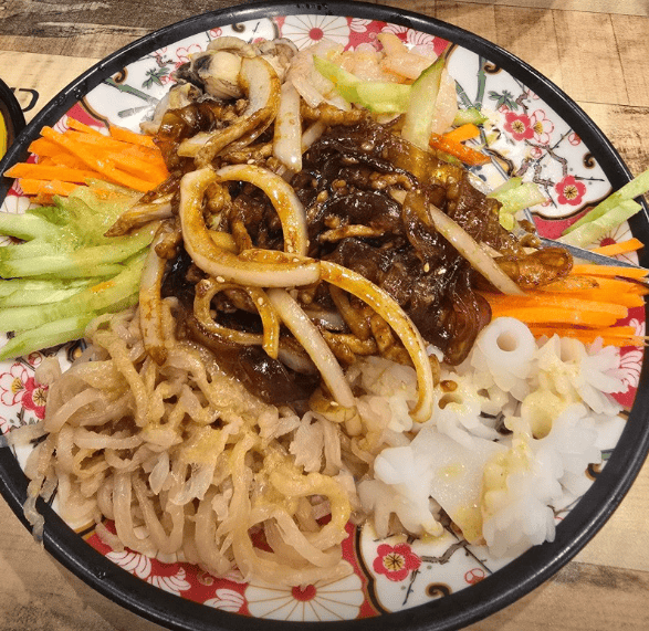Close-up of vibrant Yangjangpi with assorted shrimp, squid, and sea cucumber, ready to be mixed with its signature zesty mustard sauce for a sharp, refreshing bite.