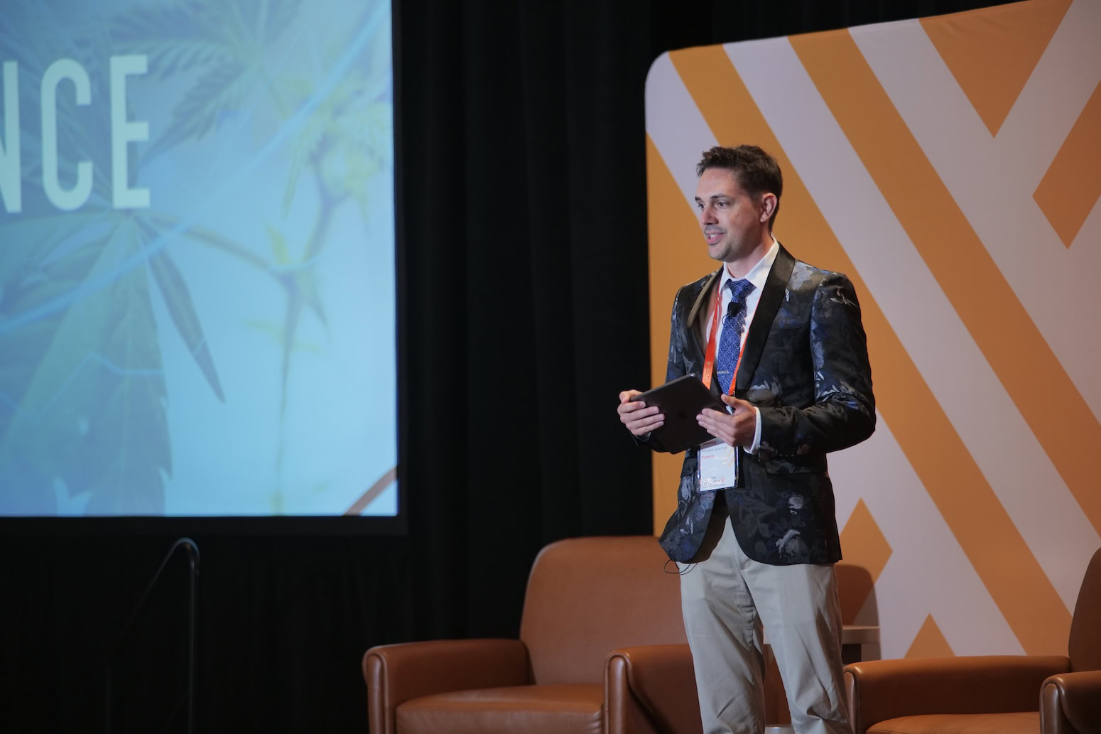 A man in a suit presents cannabis lighting technology at a cultivation conference.