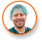 1. Facility Manager in scrubs with LED grow lights for cannabis in background 2. Chris Cortina, Holistic Industries, commercial cannabis cultivation lighting 3. Smiling facility manager under advanced cannabis lighting technology 4. Man in scrubs with lanyard, expert in cannabis cultivation science 5. Cannabis facility manager posing by commercial grow lights for cannabis.
