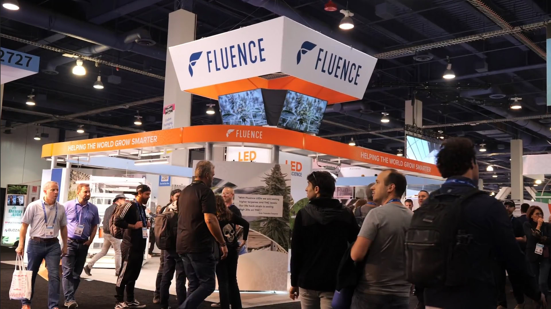 Visitors explore Fluence booth showcasing LED grow lights for commercial cannabis cultivation.