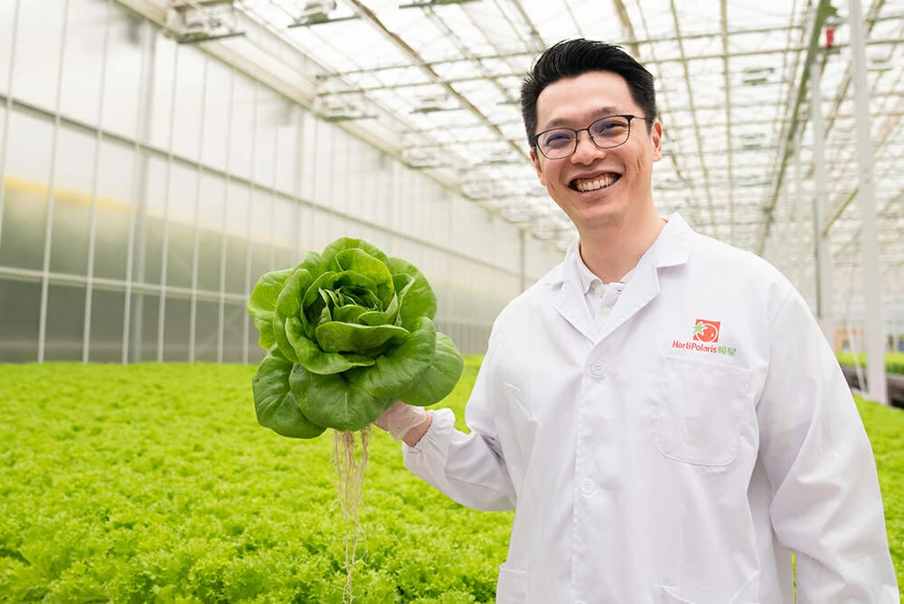 Scientist in lab coat holding cannabis plant under LED grow lights for cannabis.