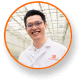 Scientist in lab coat smiles among cannabis plants under LED grow lights.