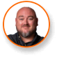 A bearded man in a dark shirt smiles, framed by an orange circle; cannabis grow lights expert.
