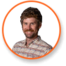 Man with curly brown hair in striped shirt smiles; orange circle frame; cannabis grow light expert.