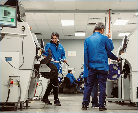 Technicians in blue uniforms inspect LED grow lights for commercial cannabis cultivation.