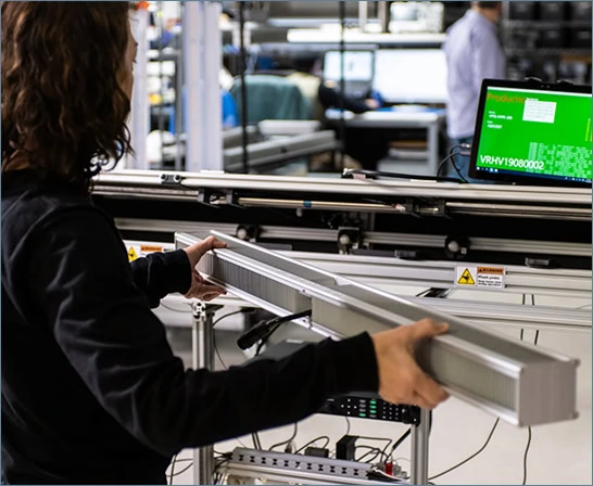 A technician tests LED grow lights for cannabis in a Fluence lab; monitor shows lighting specs.
