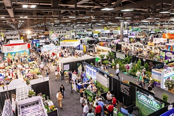 A busy cannabis expo with LED grow lights, booths on cannabis lighting tech, and attendees.