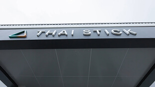 Building awning reading "THAI STICK," promoting LED grow lights for cannabis cultivation.