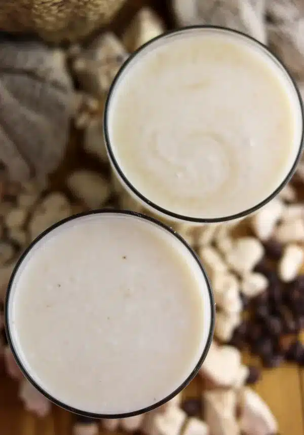 Two glasses of fresh homemade baobab juice with coconut on the table, with baobab fruit pulp in the background.