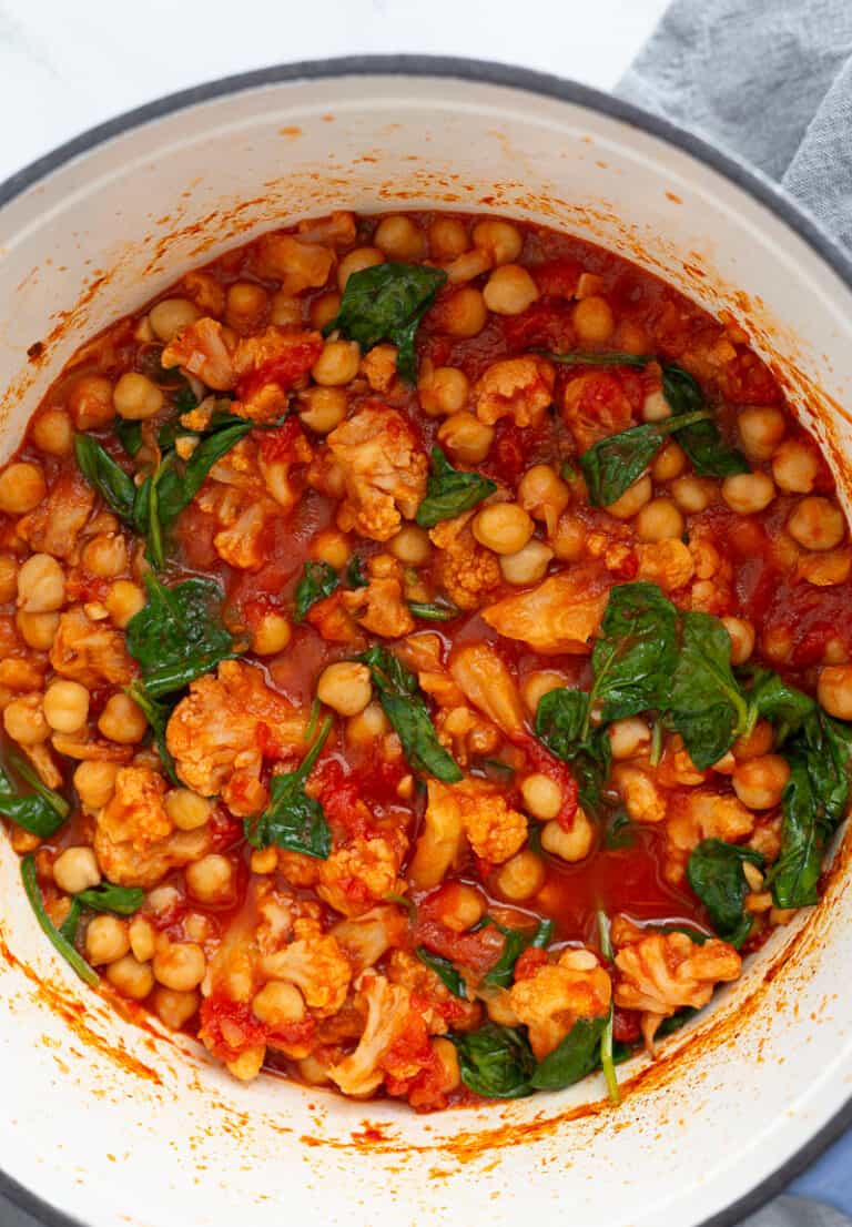 A large pot of tomato-based stew made with cauliflower and chickpeas.