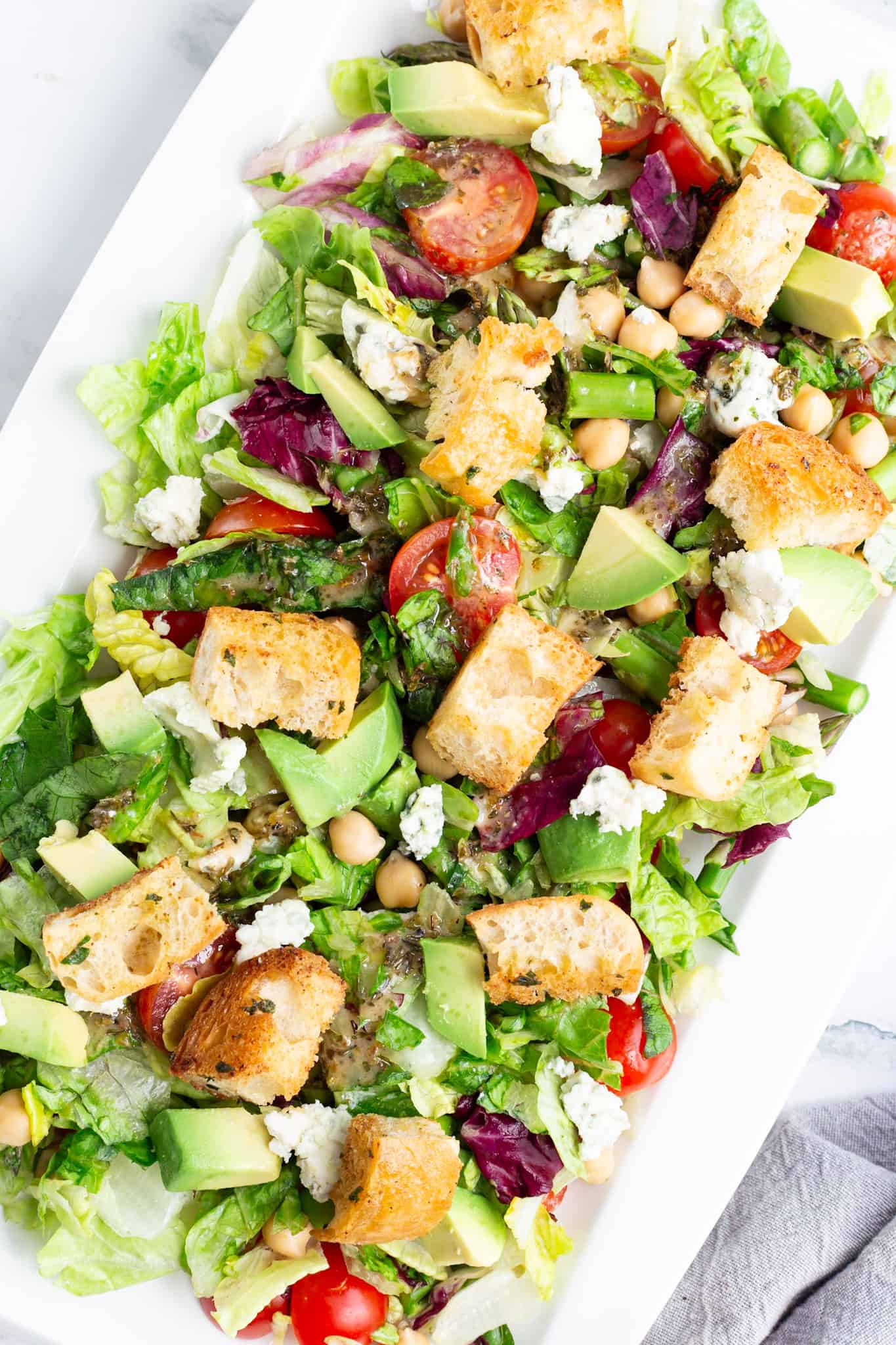 A white platter filled with blue cheese salad and topped with crispy croutons.