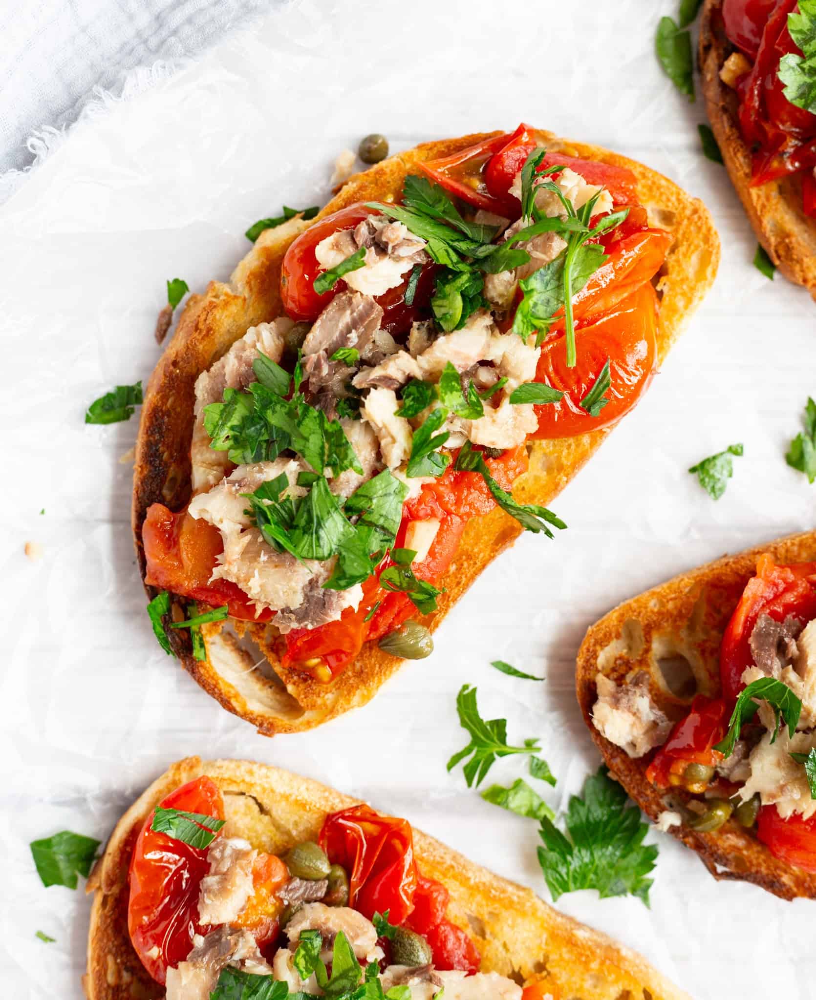 Sardines served on crispy toast with cherry tomatoes, capers, garlic, and parsley.