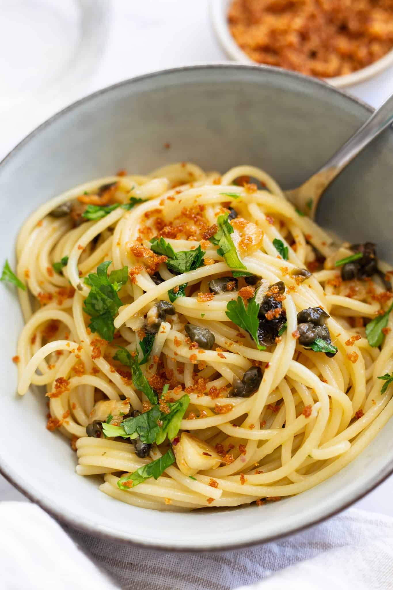 A bowl of lemon caper pasta with roasted garlic.